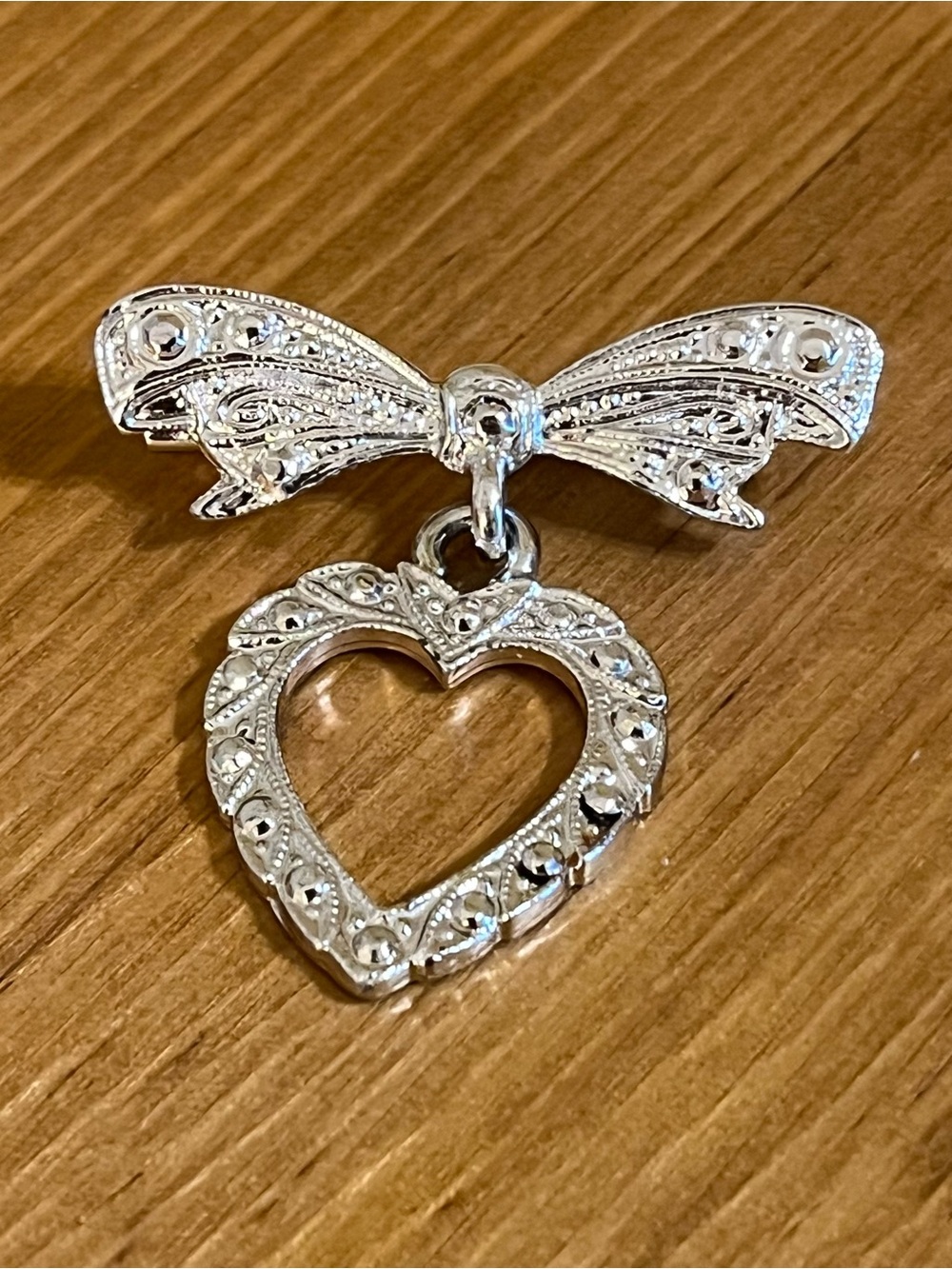Silver tone bow with dangling heart brooch with etched details 1 1/4 “ long